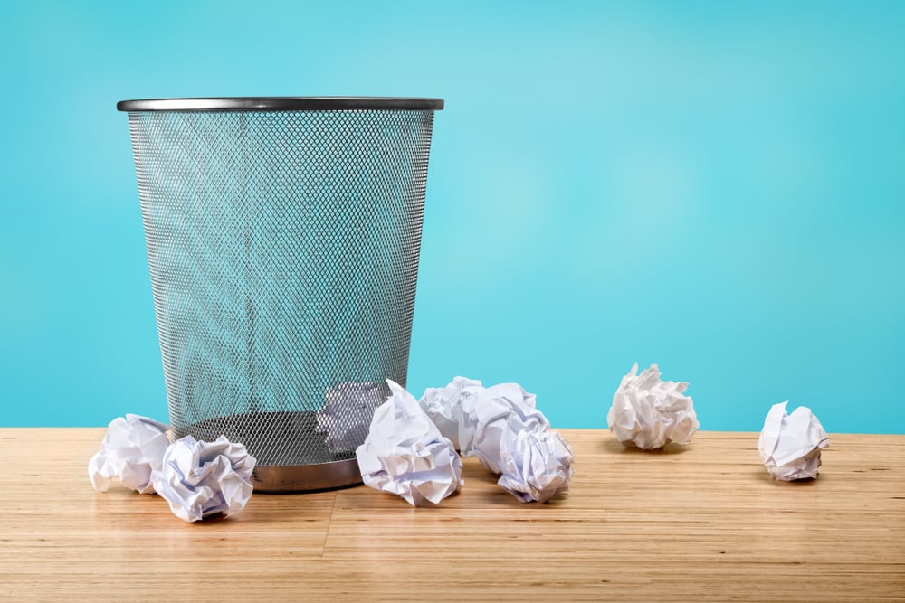 waste basket with crumpled papers around it