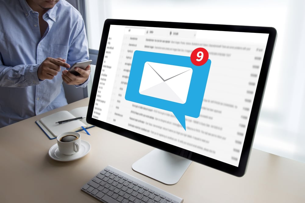 person checking email on phone next to computer